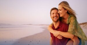 Coppia felice in spiaggia al tramonto, simbolo di serenità e progettualità finanziaria grazie alla cessione del quinto